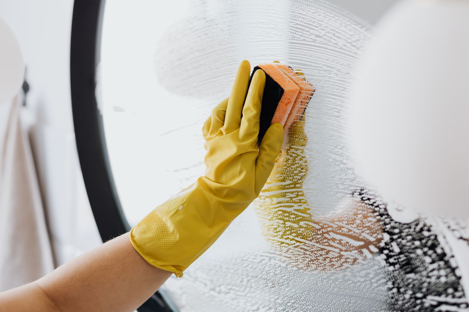 A gloved hand wiping a mirror to a streak-free, spotless shine